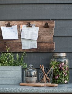 a wooden board with papers on it next to a potted plant and other items