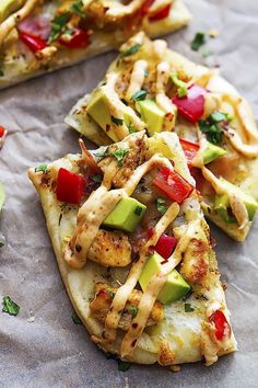 chicken, avocado and tomato pizza slices on parchment paper