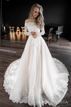 a woman wearing a white wedding dress standing in front of a black piano and looking at the camera