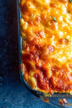 a cheesy casserole in a glass dish on a blue countertop