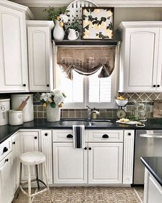 a kitchen with white cabinets and black counter tops, an area rug on the floor