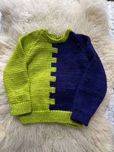 a blue and yellow sweater sitting on top of a white rug