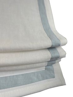 three pieces of white and grey linen with blue trims on each side, folded up