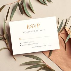 an elegant wedding rsp card with gold foil on it and greenery around it