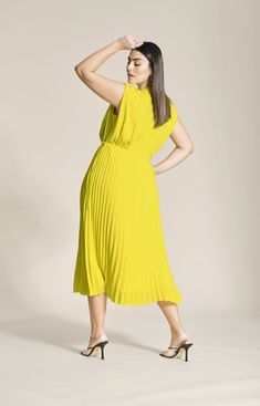 a woman in a yellow dress is posing for the camera with her hands on her head