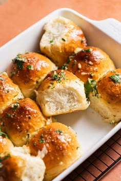 a white dish filled with rolls covered in cheese and herbs