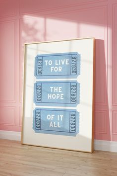 two blue tickets sitting on top of a wooden floor in front of pink walls with the words to live for the hope of it all