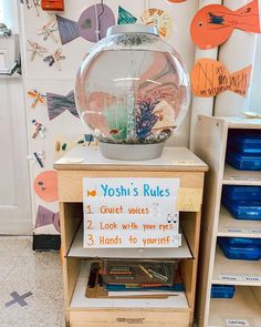 there is a fish bowl on top of a book shelf in front of other books