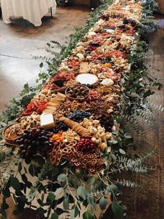 a long table covered in lots of different types of food and greenery on top of it