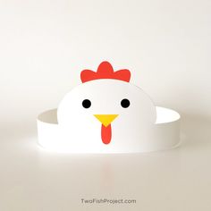 a paper chicken head on top of a white bowl with black eyes and a red comb