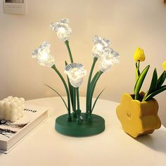 three flowers in a vase on a table next to a book