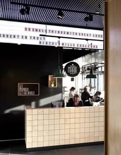 a restaurant with people sitting at the counter and hanging lights on the ceiling above it