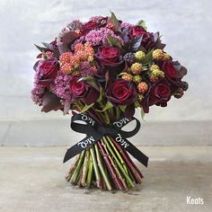 a bouquet of red roses and other flowers with a ribbon tied around the stems in a vase