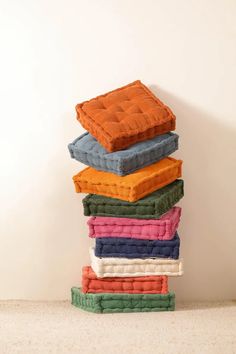 a stack of pillows sitting on top of each other in front of a white wall