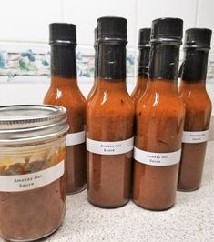 six jars of hot sauce sitting on a counter