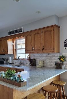 a kitchen with wooden cabinets and stools in front of an island counter top that has plants on it