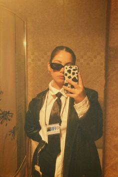 a woman taking a selfie in front of a mirror wearing sunglasses and a tie