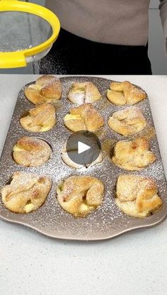 a person standing in front of a pan filled with doughnuts