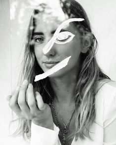 a woman with white paint on her face and eye make - up is posing in front of a mirror