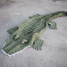 a crocheted alligator laying on the ground