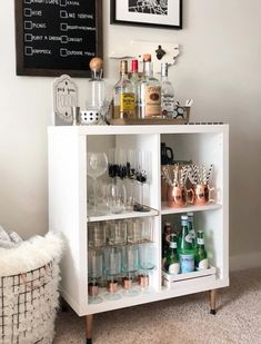 a white cabinet filled with lots of bottles and glasses