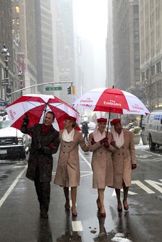 three women walking down the street in the rain with umbrellas over their heads,