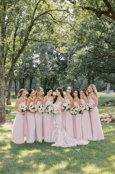 a group of women standing next to each other in front of trees