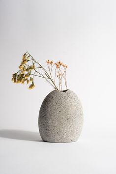 a vase with some flowers in it on a white tableclothed surface, against a plain background