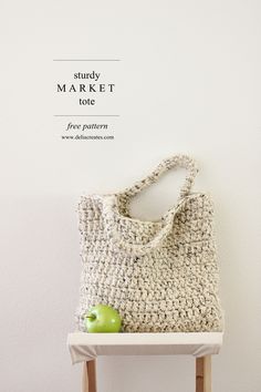 a crocheted bag sitting on top of a wooden table next to an apple