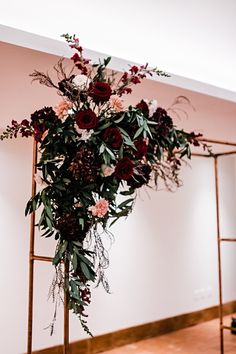 an arrangement of flowers is on display in the corner of a room with ladders