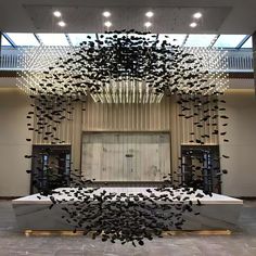 an artistic sculpture in the middle of a building with lots of black birds flying around it