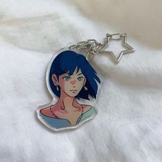 a keychain with an anime character on it sitting on a white cloth background