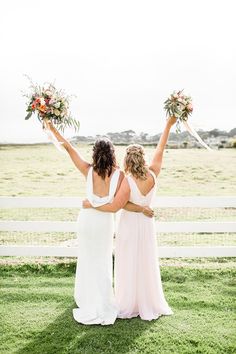 two bridesmaids holding their bouquets in the air