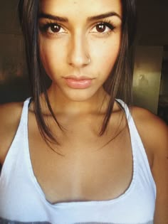 a close up of a person wearing a tank top and looking at the camera with an intense look on her face