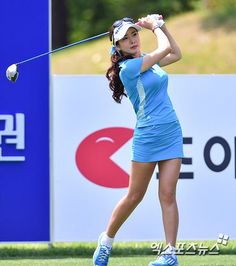 a woman swinging a golf club on top of a field