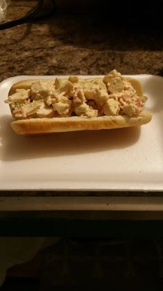 a hot dog on a bun sitting on top of a white plate with toppings