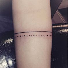 a small black dotted line tattoo on the left inner arm, with dots in it