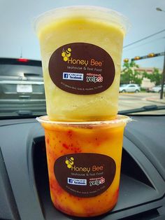 two cups of honey bee tea are stacked on top of each other in the back seat of a car