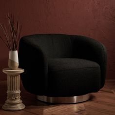 a black chair sitting next to a white vase on top of a wooden floor