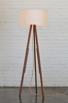 a wooden tripod floor lamp with a white shade