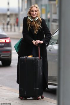 a woman is walking down the street with her luggage