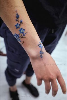 a person with a blue flower tattoo on their left wrist and hand is reaching for the camera