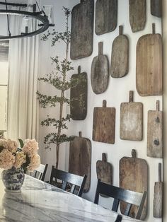 a dining room table with wooden cutting boards on the wall and flowers in a vase