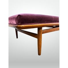 an upholstered wooden bench with a purple velvet cushion on the seat and back