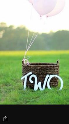 two balloons are floating in the air above a basket that says two on it and is decorated with white letters