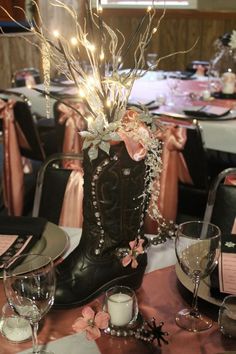 a cowboy boot centerpiece on a table with wine glasses and place settings in the background