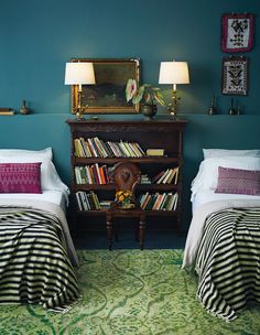 two beds in a room with green carpet and blue walls