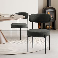 two chairs sitting in front of a table with a fire place next to it and a rug on the floor