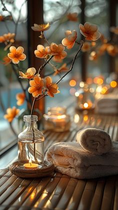 towels and candles are sitting on a table near a vase with orange flowers in it