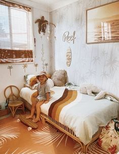 a little boy sitting on top of a bed in a room with white walls and palm trees